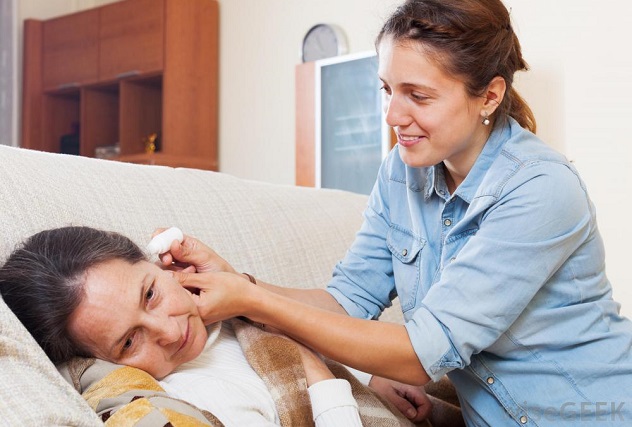 Женщина закапывает бабушке в ухо лекарство